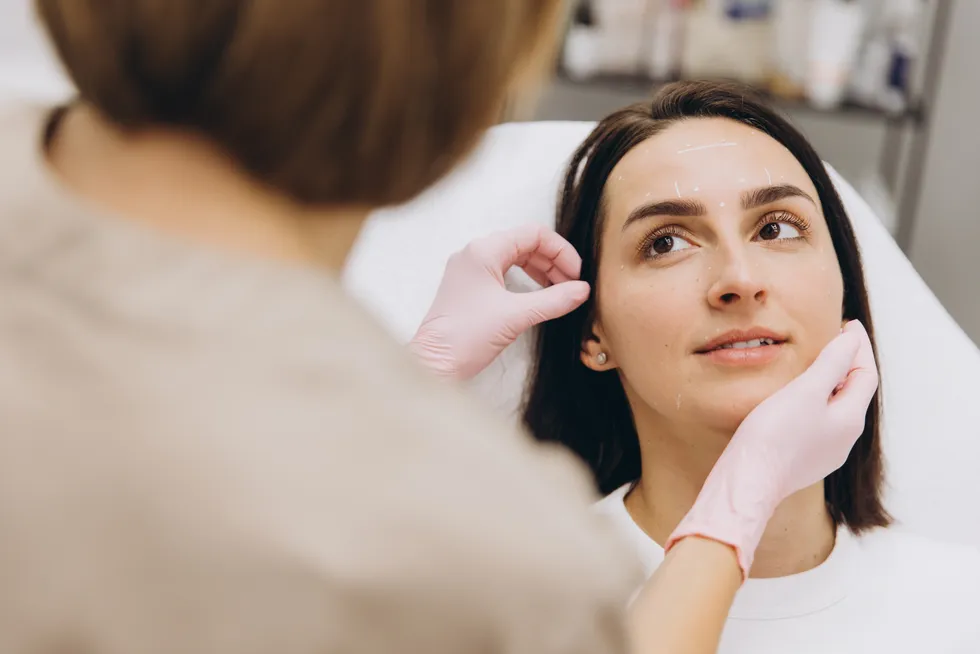 A clinician marking a patient’s face before injectable treatment