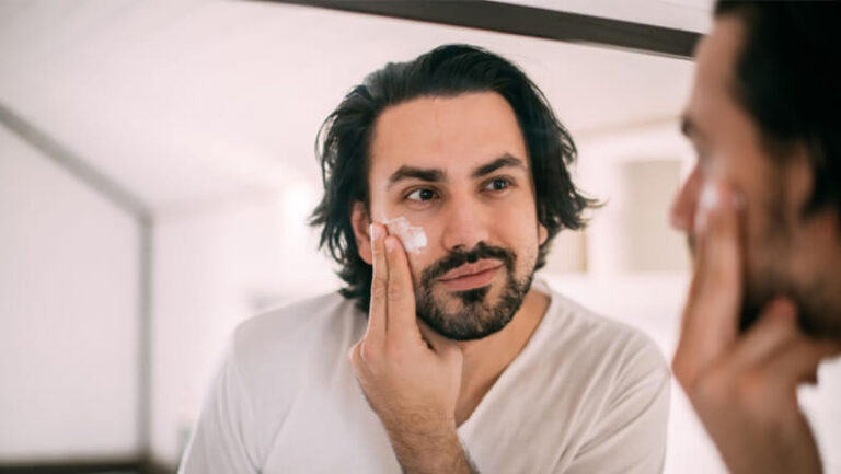 man putting facial cream on his face