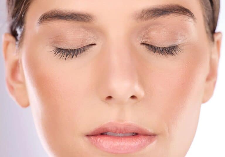Close-up of a woman’s face with closed eyes, showcasing natural makeup, smooth skin, and well-defined eyelashes. The image highlights a serene expression, emphasizing beauty and tranquility. Ideal for beauty and skincare discussions, this image conveys a sense of calm and self-care. The soft lighting enhances the skin&apos;s texture and tone, making it suitable for content related to cosmetics, skincare routines, or relaxation techniques.