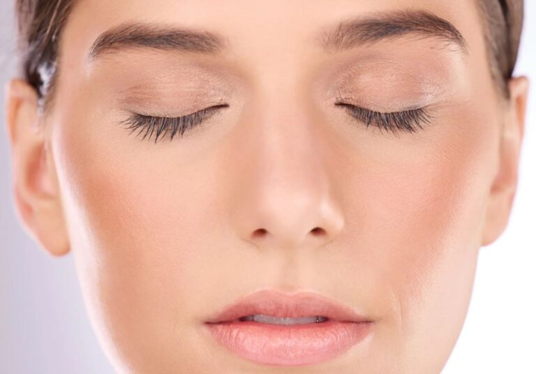 Close-up of a woman with her eyes closed, showcasing natural makeup with soft tones on her eyelids and a subtle lip color. The focus is on her smooth skin texture and well-groomed eyebrows, highlighting a serene and peaceful expression. The image emphasizes the beauty of minimalistic makeup, ideal for beauty and skincare content. Suitable for topics related to makeup tutorials, skincare routines, and relaxation techniques.