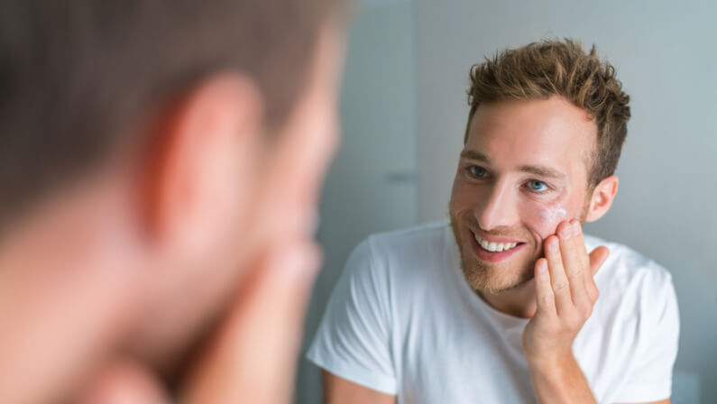 happy guy using cream on his face