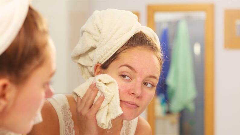 young woman using towel on her face
